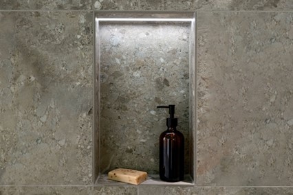 A soap dispenser and a soap bar in a nicheDescription automatically generated